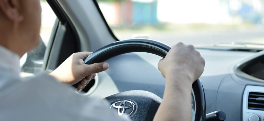 person in white long sleeve shirt driving car