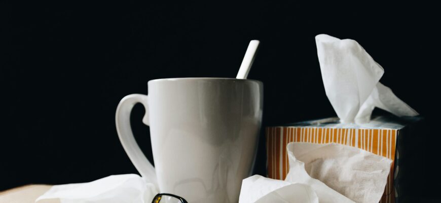 white ceramic mug on white table beside black eyeglasses