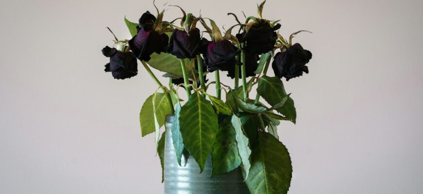a green vase filled with purple flowers on top of a table