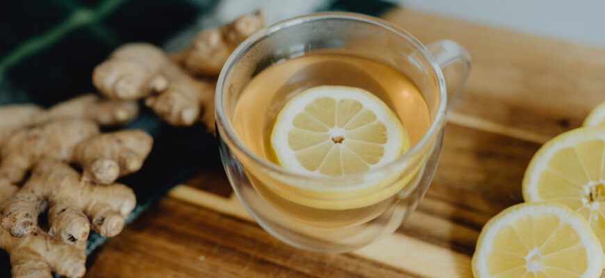 a cup of tea with lemon and ginger on a cutting board