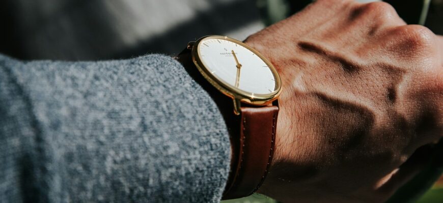 person wearing brown leather strap gold round analog watch