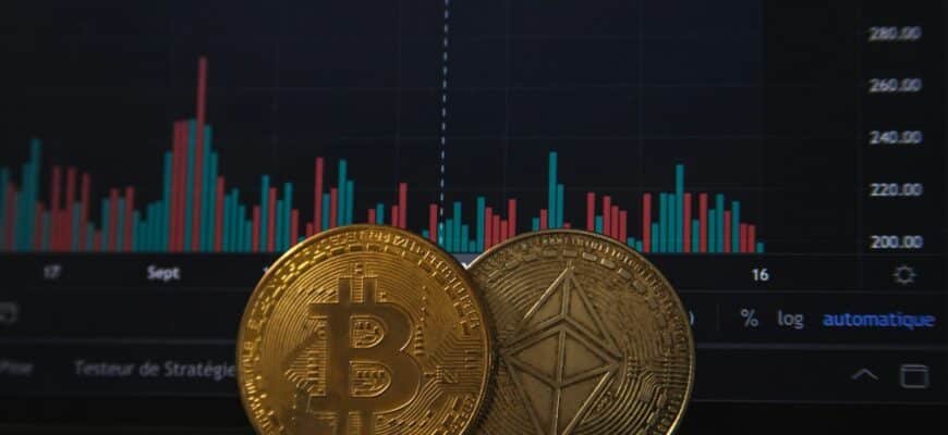 Gold Bitcoin and silver Ethereum coins resting on a laptop keyboard before a trading chart